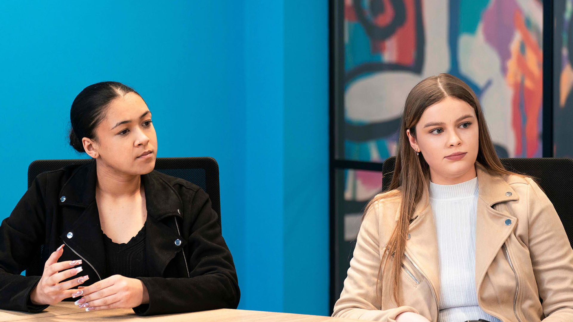 Two young women in a workplace discussion at a table