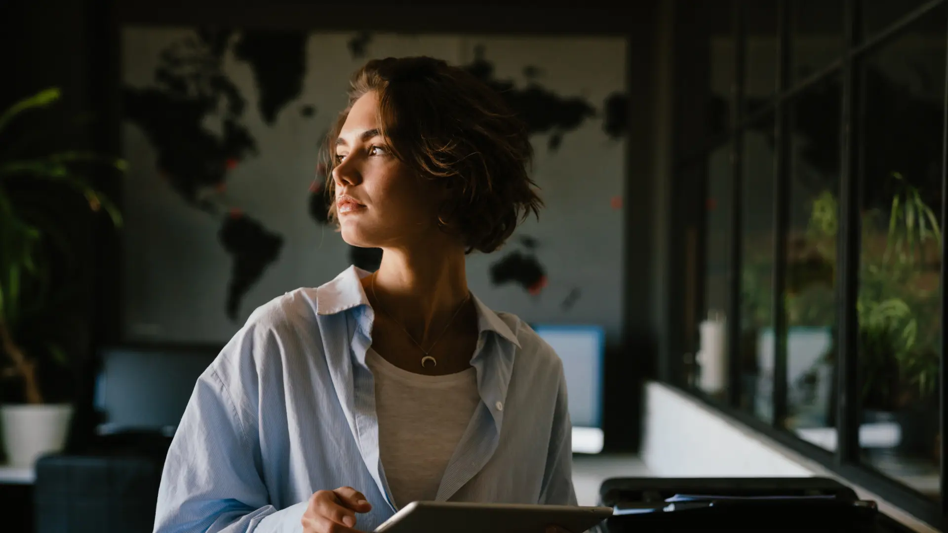A young professional pausing in thought in a modern office